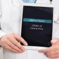 Close-up of male doctor showing medical covid-19 corona virus report on a tablet