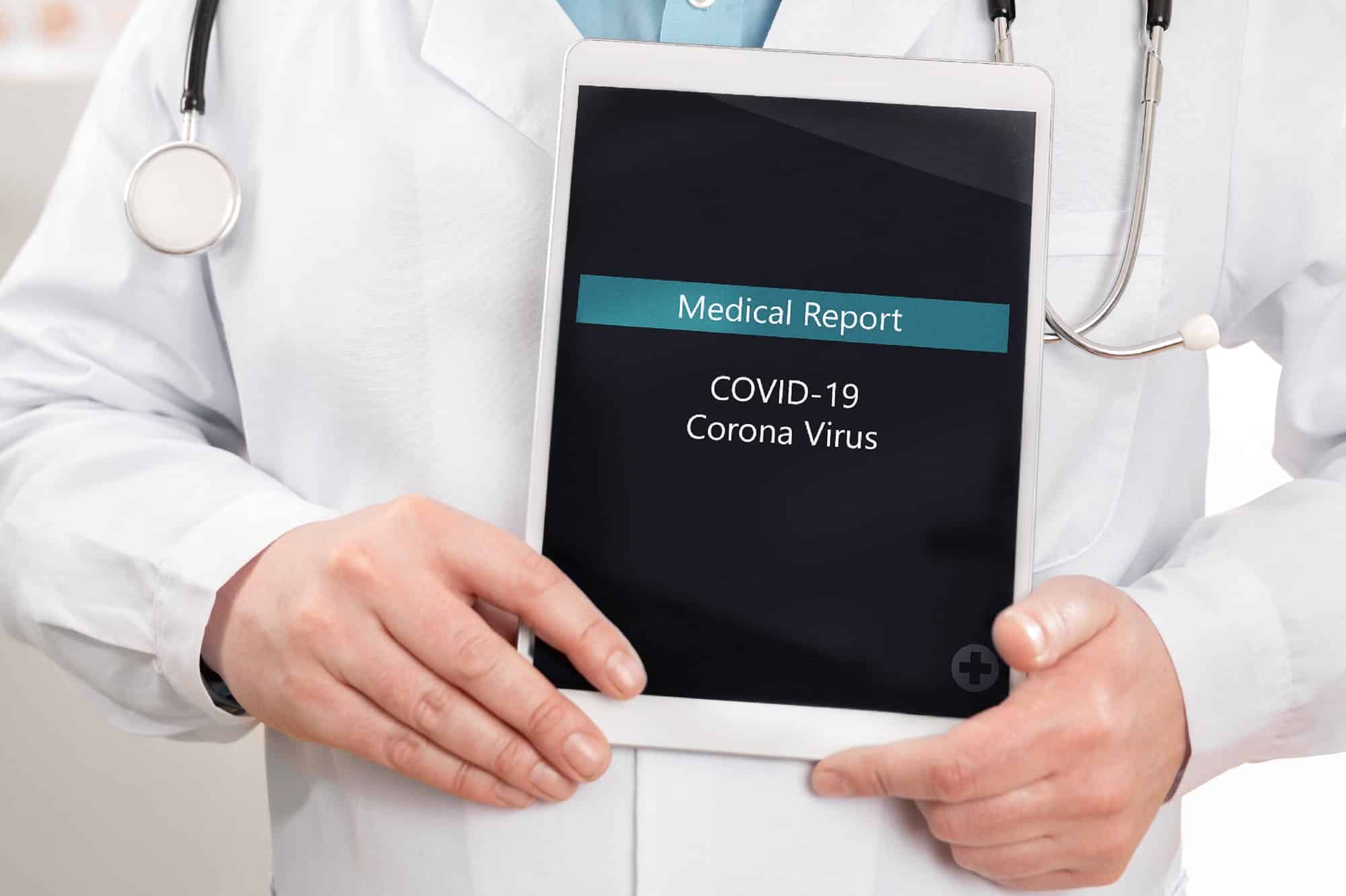 Close-up of male doctor showing medical covid-19 corona virus report on a tablet