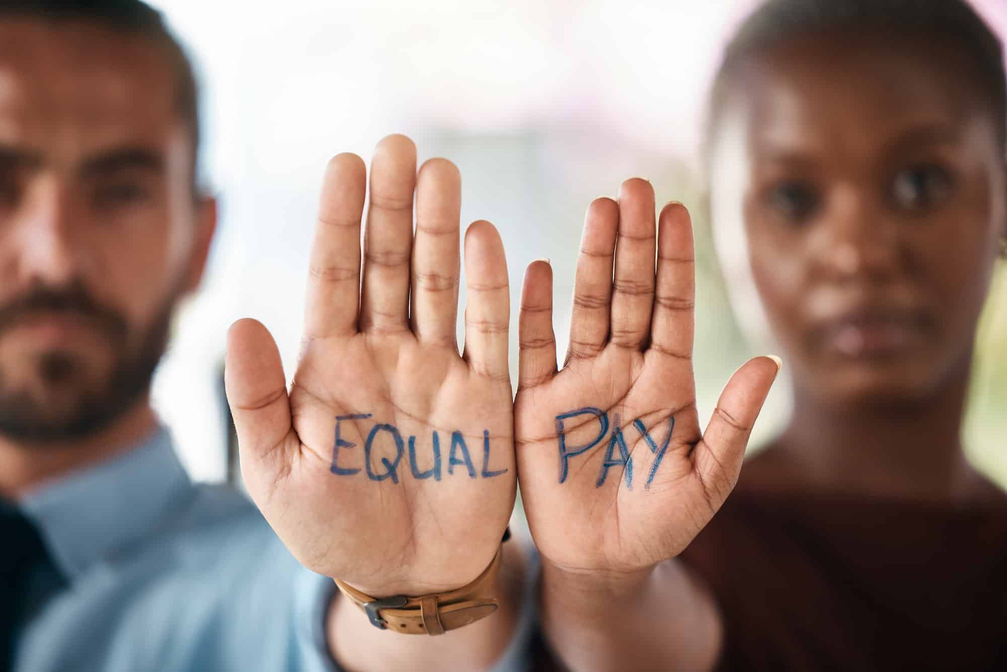 Hands, equality and empowerment with a business man and woman showing an equal pay notice in their