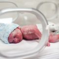 Newborn baby covered in vertix in incubator